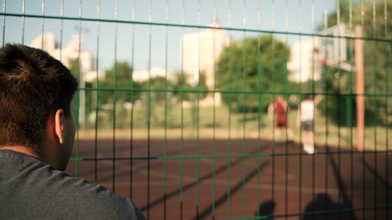 back-view-of-a-young-man-sitting-and-watching-basketball-training
